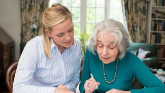 Woman helping elderly woman with finance